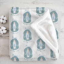 White blanket with blue religious icon pattern on a light wooden background
