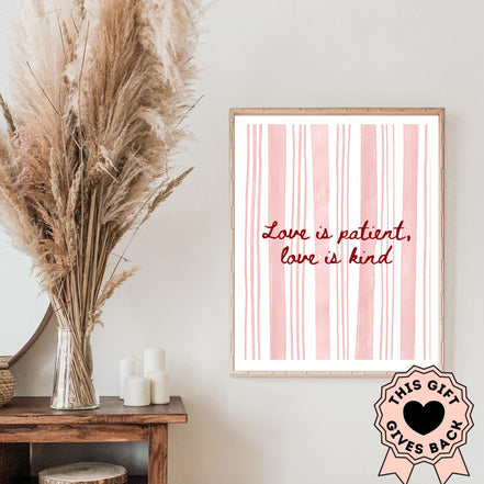 Framed artwork with 'Love is patient, love is kind' quote on a pink background, next to dried pampas grass and candles.